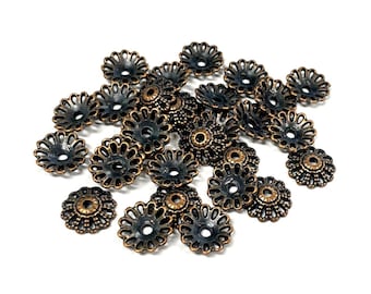 May include: A pile of 20 antique gold-toned metal flower-shaped embellishments with a black center. The embellishments have a decorative, intricate design.