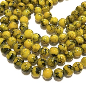 May include: A strand of yellow glass beads with black marbling. The beads are round and have a glossy finish.