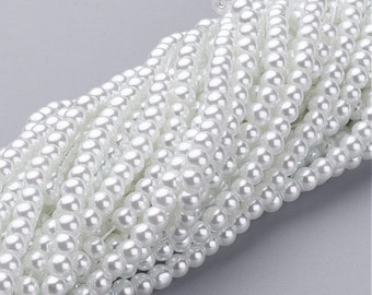 May include: A strand of white faux pearl beads. The beads are round and smooth, and they are strung together on a clear thread.