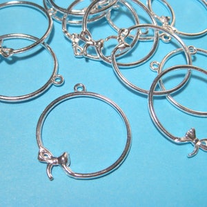 May include: Silver-toned metal hoops with a bow detail. The hoops are approximately 1 inch in diameter.