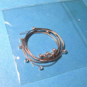 May include: A set of silver guitar strings with silver ball ends in a clear plastic bag.