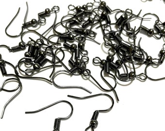 May include: A pile of black metal earring hooks with spring closures. The hooks are scattered on a white surface.