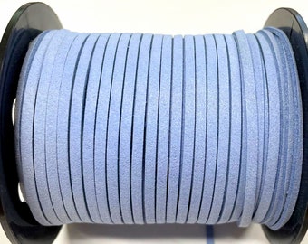 May include: A spool of light blue suede cord, wound tightly around a black plastic spool. The cord is smooth and has a slightly textured surface.