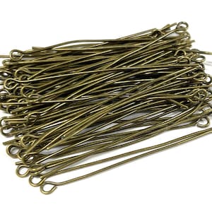 May include: A pile of gold-toned head pins with a loop at the top. The pins are about 1 inch long.