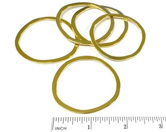 May include: Five gold-colored metal rings of varying sizes, arranged on a white surface with a ruler for scale. The rings are approximately 1 inch in diameter.