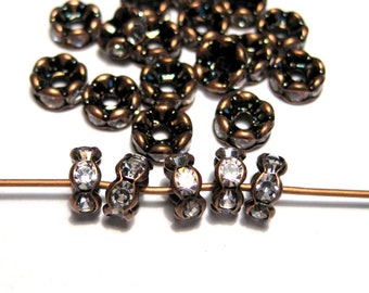 May include: A group of antique copper-toned metal beads with clear crystal accents. The beads are strung on a wire and are perfect for jewelry making.