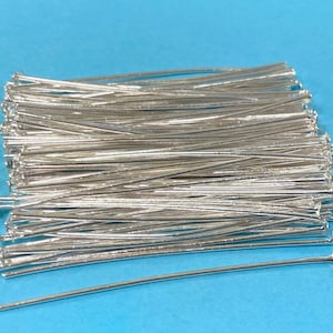 May include: A large pile of silver-colored head pins, with one pin extended out to the right. The pins are used for jewelry making and crafts.