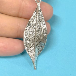 May include: Silver leaf charm with a textured surface and a loop at the top for hanging.