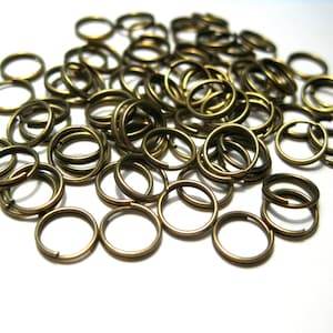 May include: A large pile of gold-colored metal jump rings. The rings are all the same size and are arranged in a random pattern.