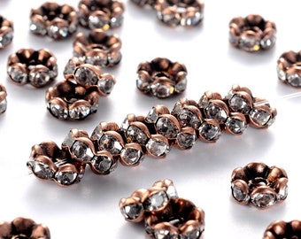 May include: A scattering of copper-toned metal bead spacers with clear crystal accents. Each spacer is adorned with a ring of small, faceted crystals.