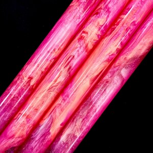 Può includere: Primo piano di quattro oggetti cilindrici vibranti con finitura lucida. La tavolozza dei colori passa dal magenta intenso al rosa brillante e all'arancione, con motivi a vortice. Lo sfondo è nero.