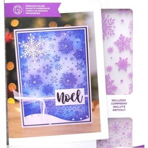 May include: A Gemini 2-piece embossing folder set featuring a winter theme. The set includes a card with a blue and white snowflake design and the word "Noel". The card measures 5" x 5" (12.7cm x 12.7cm).