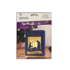 May include: A Gemini embossing folder with a Christmas card design. The card features a silhouette of the nativity scene with the text "Joy to the World". The package is 5" x 7" (12.7cm x 17.8cm).