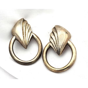 May include: A pair of vintage silver-toned earrings. Each earring features a fan-shaped top connected to a circular hoop. The earrings have a tarnished, aged appearance, suggesting they are antique or vintage jewelry.