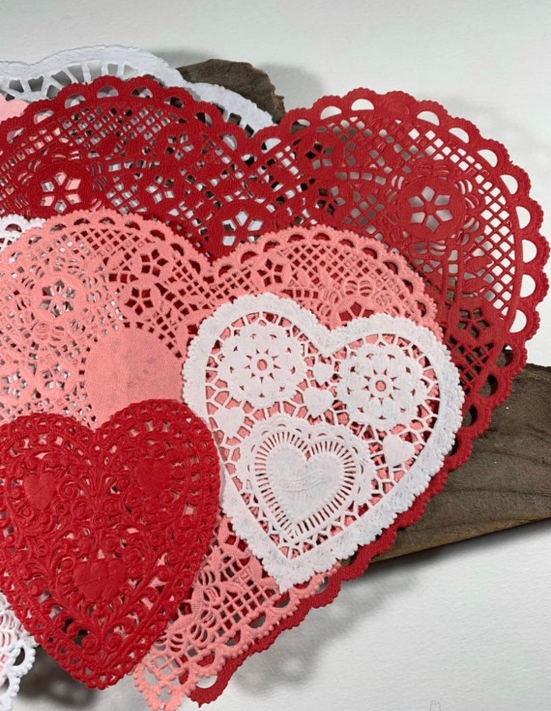 Peut inclure: Assortiment de doilies en papier en forme de c&oelig;ur rouge, rose et blanc avec des motifs de dentelle complexes.