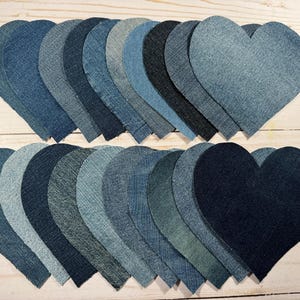 May include: A collection of 20 denim heart shapes in various shades of blue, arranged in two rows. The hearts are all the same size and shape, and they are all made of denim fabric.