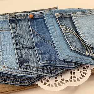 May include: A collection of seven denim pockets in various shades of blue, arranged in a staggered pattern. The pockets are sewn together and have a raw edge finish.