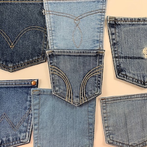 May include: A collection of seven denim pockets in various shades of blue, some with stitching details and one with a small hole.