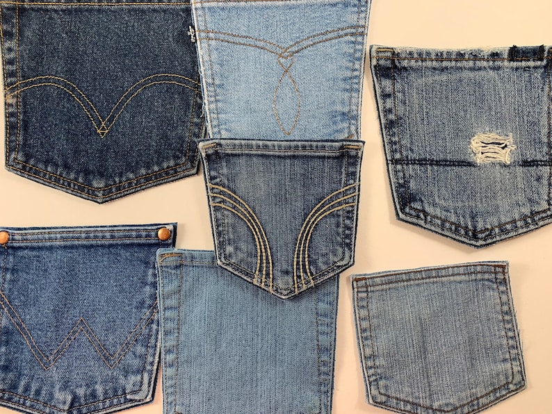 May include: A collection of seven denim pockets in various shades of blue, some with stitching details and one with a small hole.