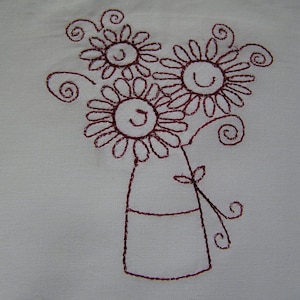 May include: Embroidered design of three stylized flowers with smiling faces in a vase. The flowers are brown and the vase is outlined in brown.