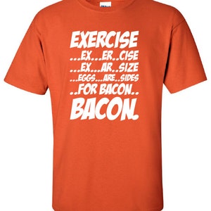 May include: Orange t-shirt with white text that reads "EXERCISE...EX...ER..CISE...EX...AR..SIZE...EGGS...ARE..SIDES..FOR BACON..BACON."