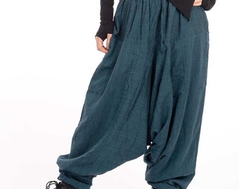 Peut inclure: Une femme portant un chemisier noir à manches longues et un pantalon ample bleu sarcelle. Elle porte des bottes noires à lacets.