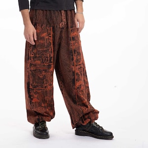 May include: A person wearing a black long-sleeved shirt and orange and black patterned trousers. The trousers have a loose fit and are gathered at the ankles.