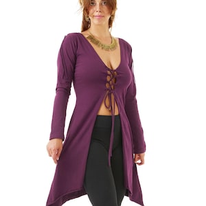 May include: A long-sleeved, plum-colored tunic with a lace-up front, paired with black leggings and black ankle boots. The tunic has a high-low hemline and a deep V-neck. A gold-colored necklace is worn.