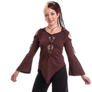 May include: A woman wearing a brown, long-sleeved, hooded top with a lace-up front and black, wide-leg trousers.