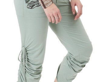 May include: Sage green yoga pants with a drawstring waist and a feather design on the left leg. The pants have a gathered detail at the bottom of the legs.
