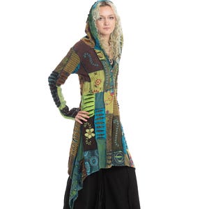 May include: A patchwork hooded jacket with a variety of colors, including brown, green, blue, and yellow. The jacket has a long, flowing design and is paired with black pants. The jacket features floral and geometric patterns.