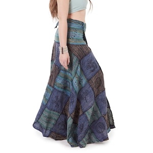 May include: A long, patchwork skirt in shades of blue, green, and brown, with geometric and symbolic patterns. The skirt is worn with a light blue halter top. The style is bohemian and relaxed, suitable for casual wear.