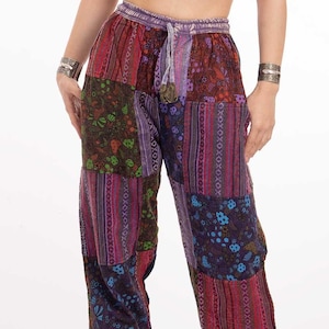 May include: A woman wearing a burgundy halter top with a silver key pendant necklace and patchwork pants with a floral and striped pattern.