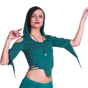 May include: A woman wearing a teal green hooded top with a turquoise pendant necklace and matching teal green pants with decorative stitching.