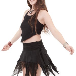 Può includere: Top e gonna neri con finiture in pizzo. La gonna ha un design a strati e un orlo in pizzo. L'outfit è in stile bohémien. La modella indossa una collana e braccialetti.