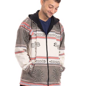 May include: A gray and white hooded jacket with a zipper closure and a patterned design featuring black eyes and suns. The jacket has a black hood and is made of a soft, comfortable fabric.