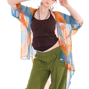May include: A woman's outfit featuring a brown halter top, olive green pants, and a sheer, colorful kimono-style jacket. The jacket has blue, orange, and white stripes. The outfit is bohemian in style.