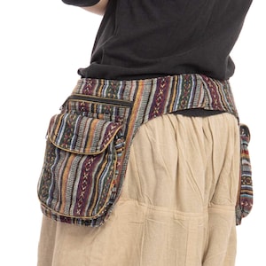 Puede incluir: Un cinturón de tela a rayas multicolores con dos bolsillos grandes a cada lado. El cinturón se lleva alrededor de la cintura y tiene una cremallera.