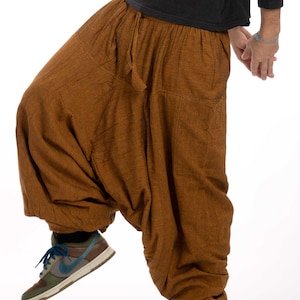 Könnte beinhalten: Eine braune, lockere Hose mit einem Kordelzugbund. Die Hose ist aus einem weichen, strukturierten Stoff gefertigt und hat eine lockere, bequeme Passform.