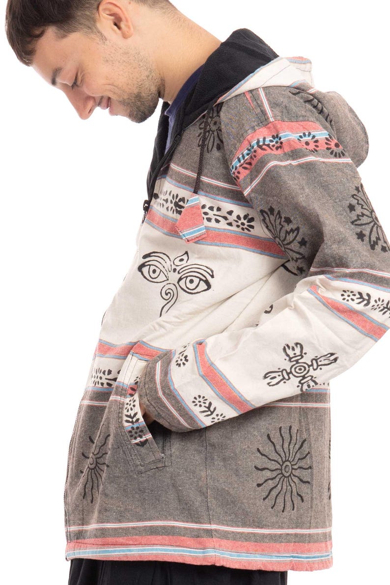 May include: A hooded jacket with a striped pattern in shades of gray, pink, and blue. The jacket has a zipper closure and a drawstring hood. The fabric is printed with black floral designs and a symbol with two eyes.