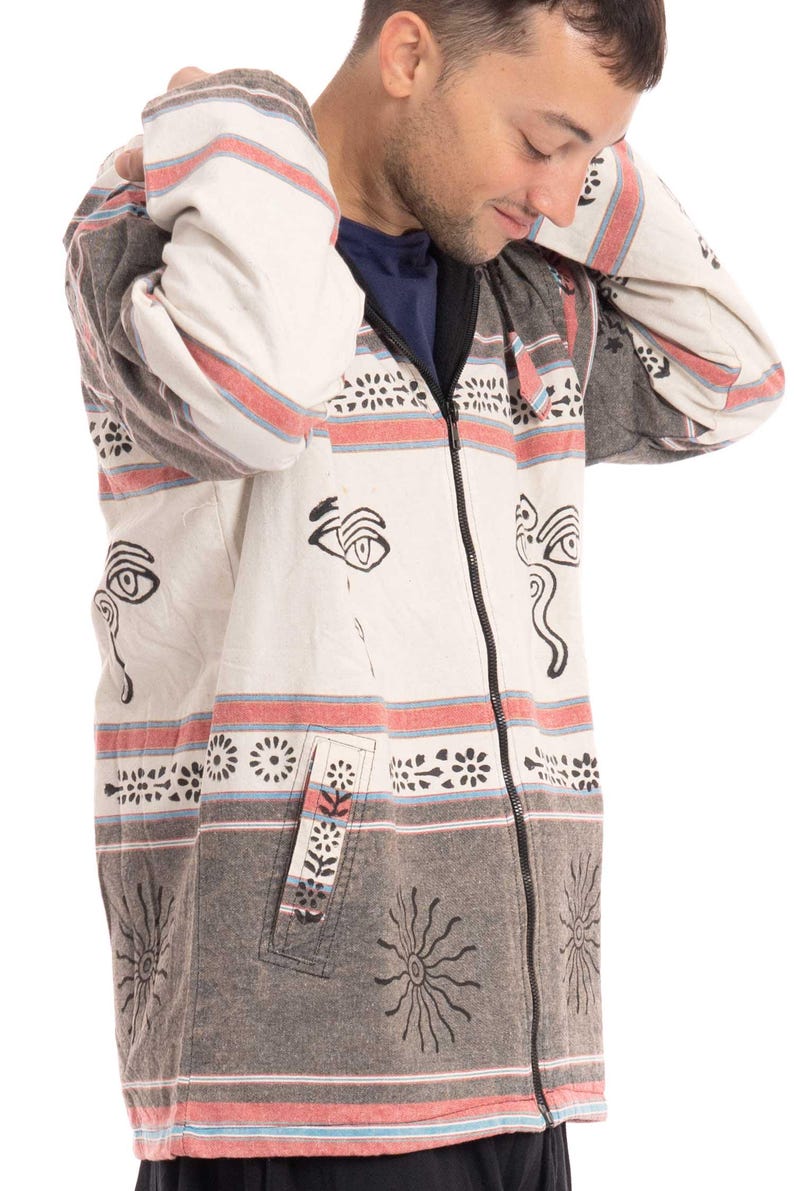 May include: A white and gray striped hooded jacket with black and white eye and sun designs. The jacket has a zipper closure and a pocket on the left side.