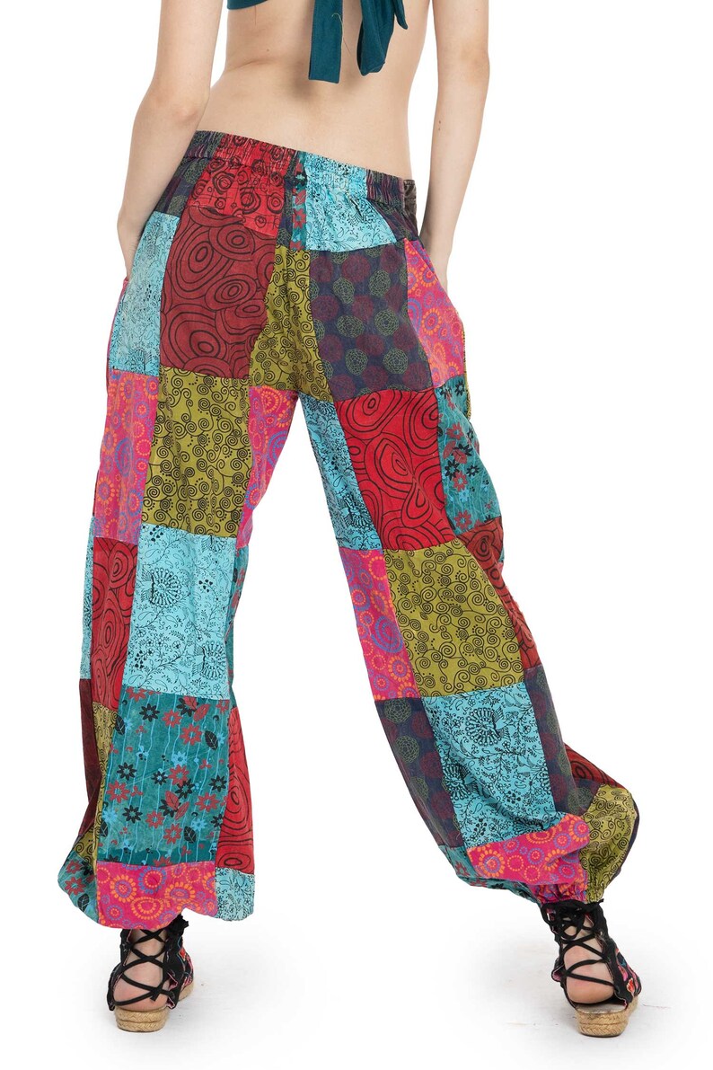 May include: Patchwork trousers with a colourful, geometric pattern in shades of red, green, blue, and pink. The trousers have a wide leg and a loose fit.