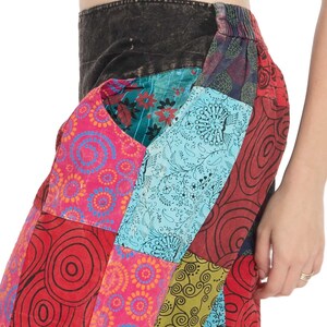 May include: Patchwork trousers with a colourful design featuring swirls, circles, and floral patterns in shades of red, pink, blue, green, and black.