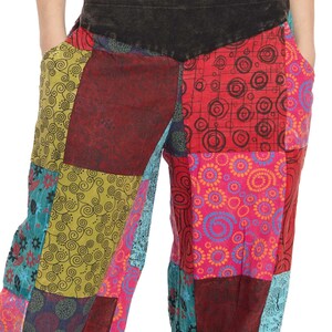 May include: Patchwork trousers with a variety of colourful patterns, including swirls, circles, and floral designs. The trousers have a black waistband with a zipper.