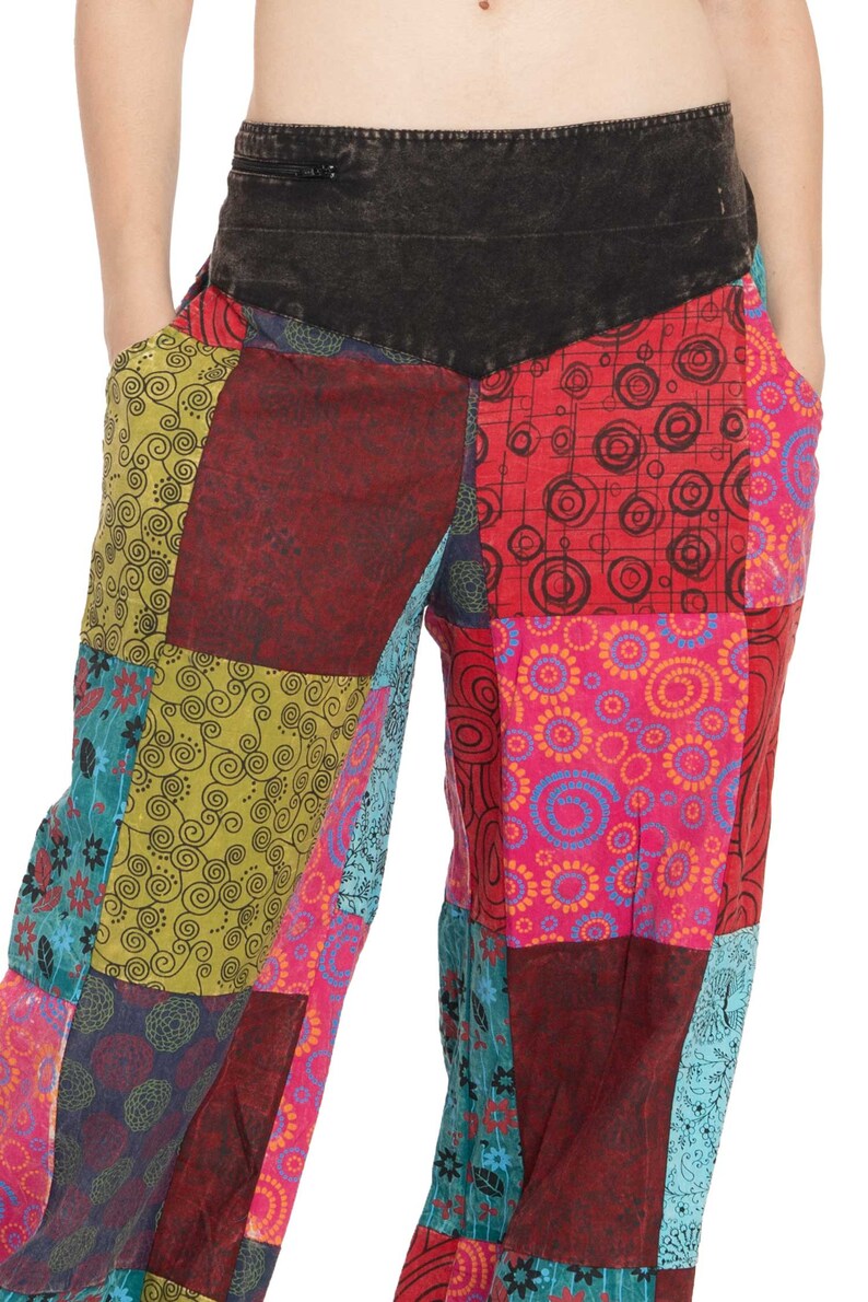 May include: Patchwork trousers with a variety of colourful patterns, including swirls, circles, and floral designs. The trousers have a black waistband with a zipper.