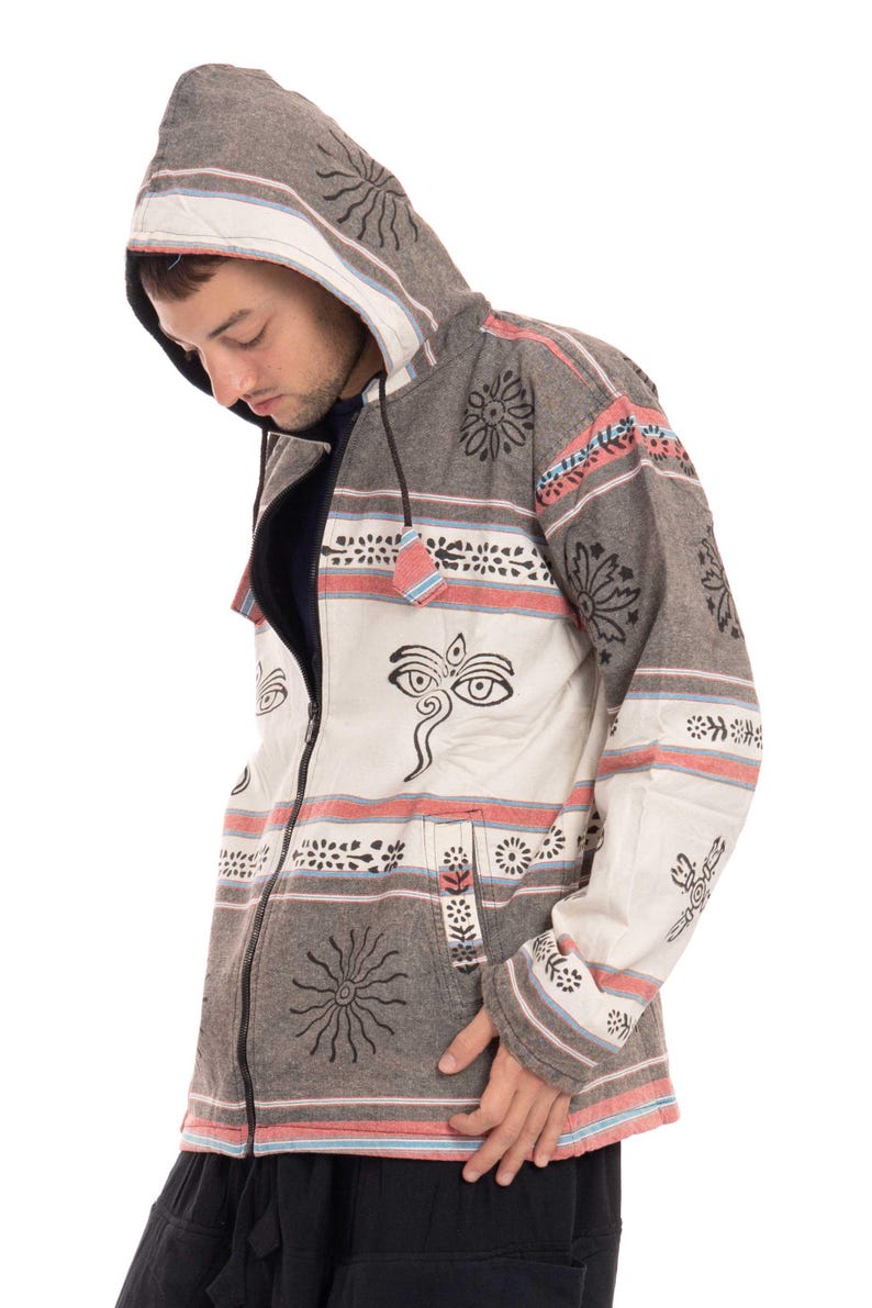 May include: A gray and white hooded jacket with a zipper closure and a patterned design featuring black and white floral motifs, a sun symbol, and a stylized eye design. The jacket has a hood with a drawstring.