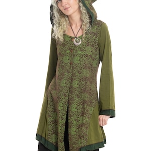 Könnte beinhalten: Olivgrüne Tunika mit braunem Blumenmuster, langen Ärmeln und einer spitz zulaufenden Kapuze. Die Tunika hat eine geteilte Vorderseite und dunkelgrüne Verzierungen. Ein silberner Anhänger hängt an einer schwarzen Kordel.