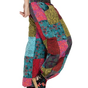 May include: Patchwork trousers with a colourful, geometric pattern in shades of red, blue, green, and pink. The trousers are loose-fitting and have a wide leg.