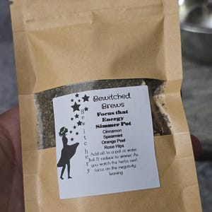 May include: A brown paper bag containing dried herbs for a simmer pot. The label reads "Bewitched Brews" and lists ingredients like cinnamon and spearmint. A silhouette of a witch is also on the label.