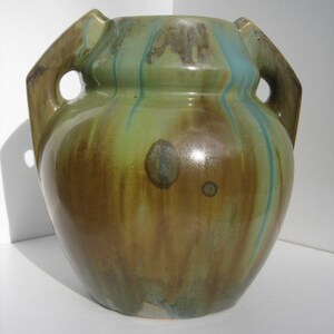 May include: A green and brown ceramic vase with two handles. The vase has a mottled glaze with streaks of blue and green.